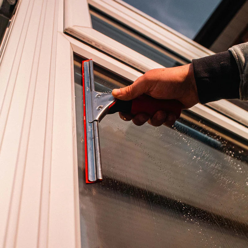 Window cleaner using a window cleaning squeegee on commercial glass windows for streak-free exterior and interior window cleaning services.