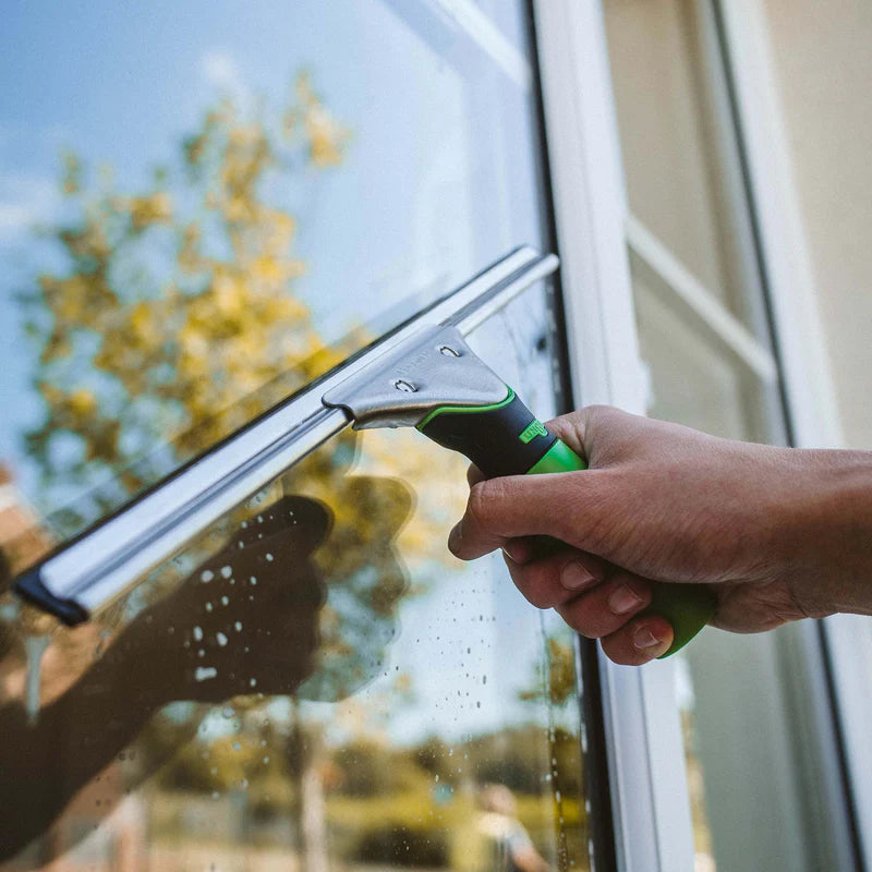 Window cleaner using a squeegee to clean glass windows for streak-free commercial and residential window cleaning results.