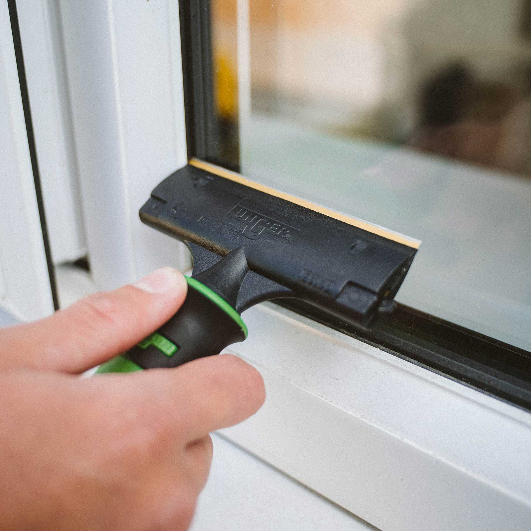Window Cleaner using Unger ErgoTec® Glass Scraper featuring an ergonomic non-slip handle and professional-grade stainless steel blade, designed for removing paint, stickers, tape residue, bird droppings, and stubborn debris from windows and glass surfaces.